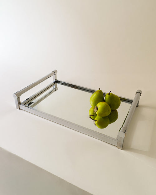 Adnet 1940s table mirror shown at an angle with green pears on its mirrored surface
