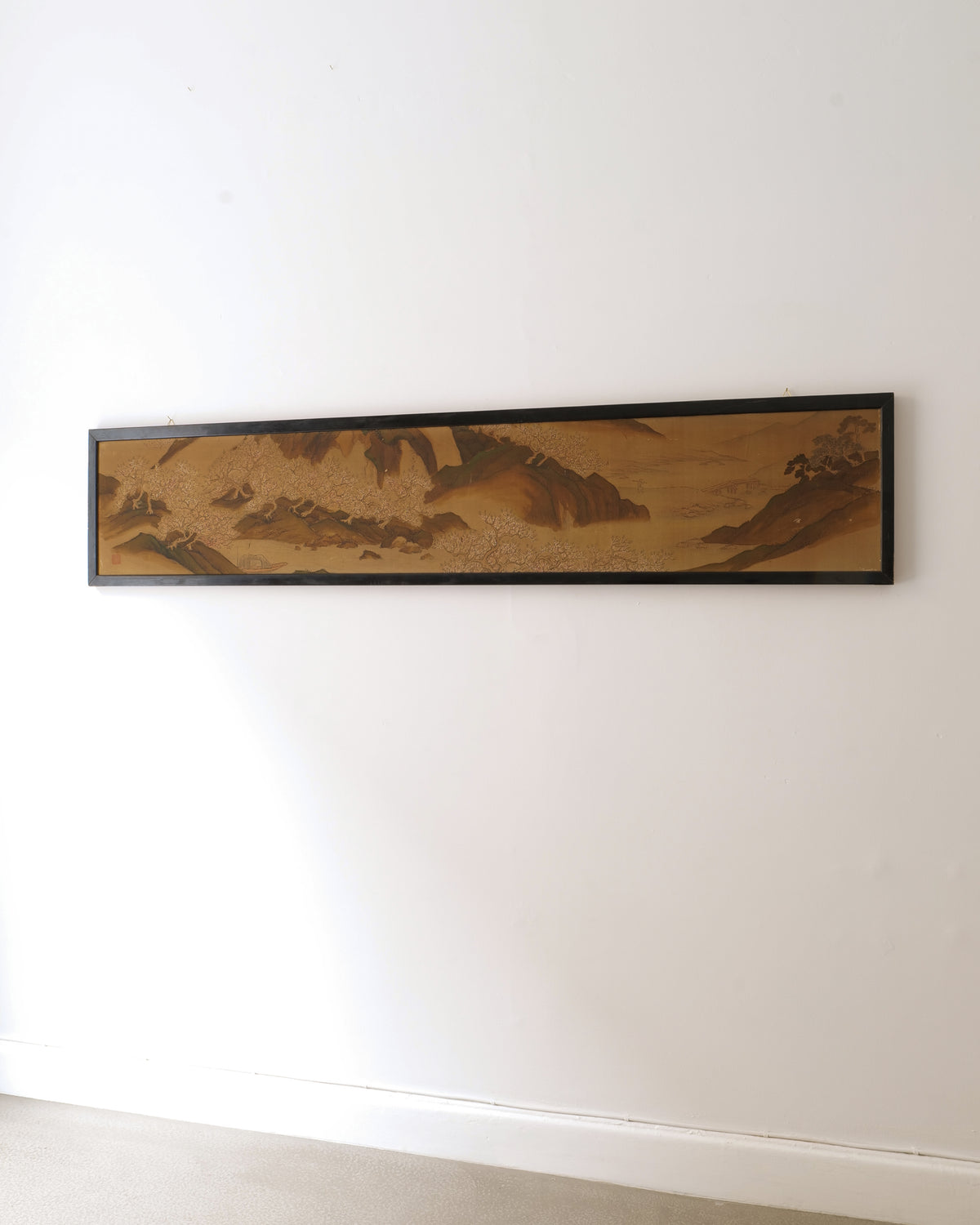 Long horizontal Japanese silk panel from around 1850 shown mounted on a white wall
