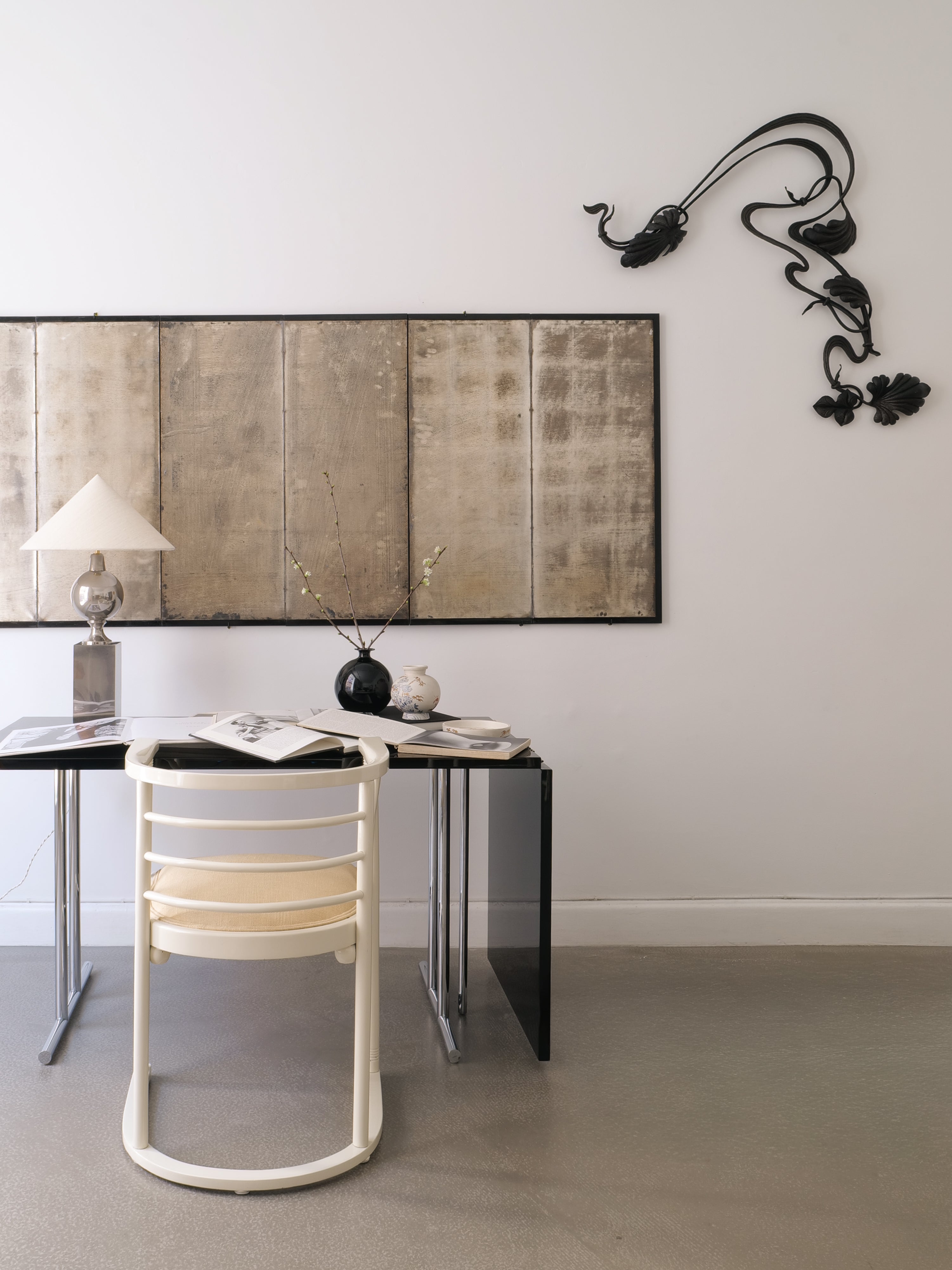 Modern interior with a black desk, white chair, and decorative wall art.