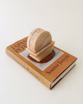 Banded onyx coasters stacked upright in their stone holder on a book
