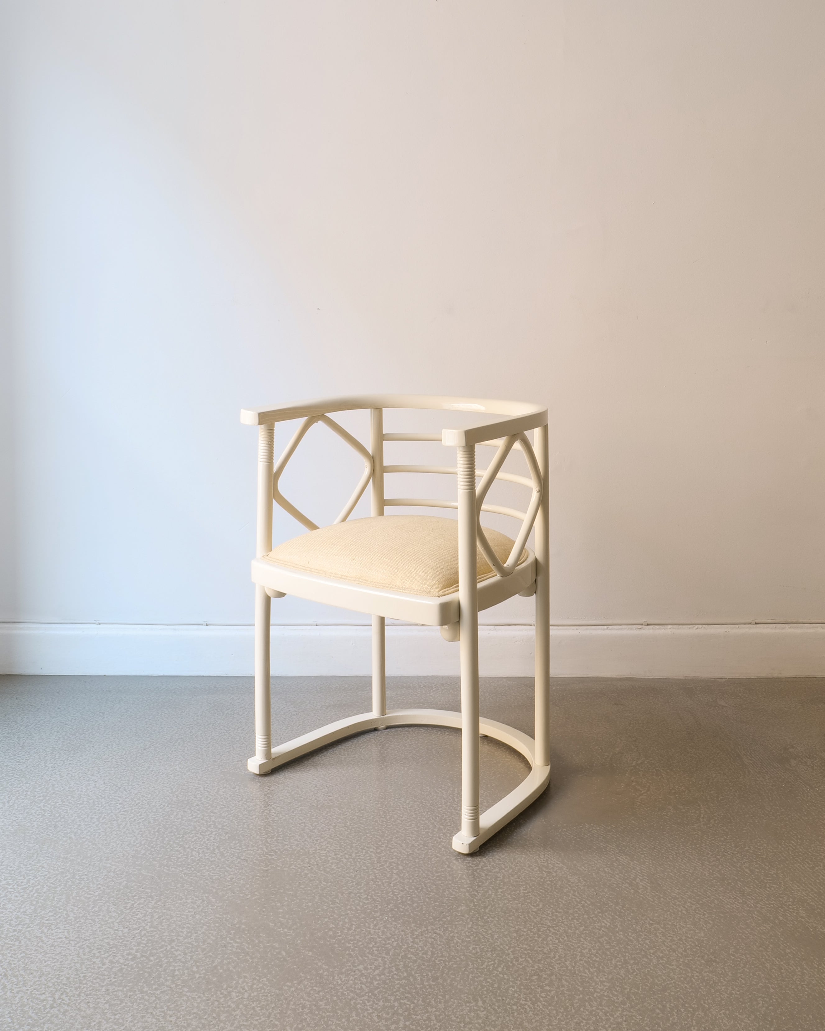 White lacquered Josef Hoffman chairs with beige seat on a plain floor and wall background