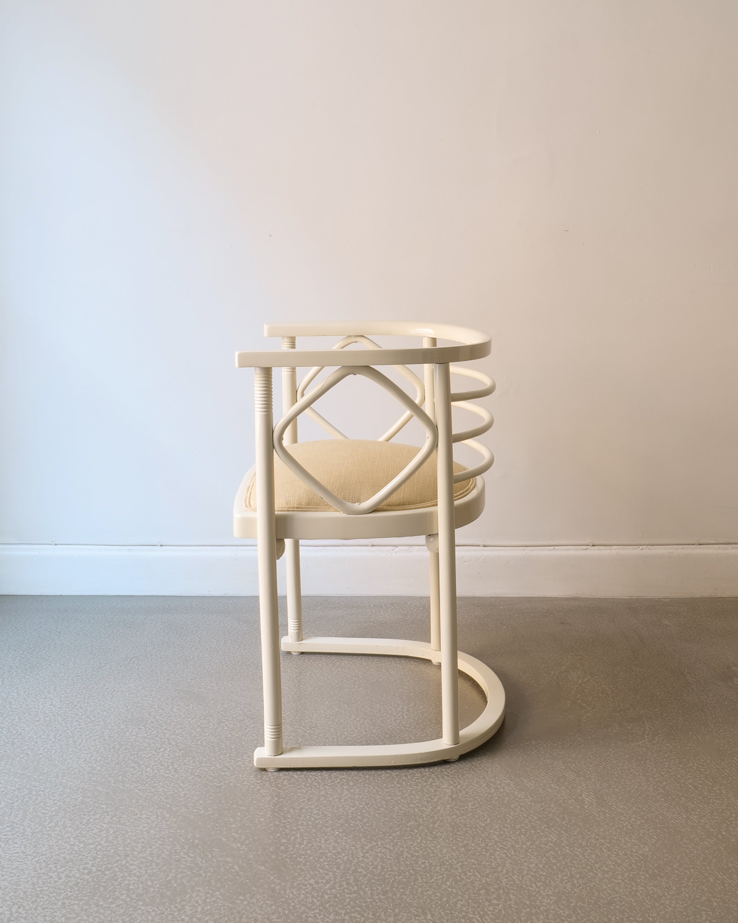 White lacquered Josef Hoffman chairs with beige seat on a plain floor and wall background