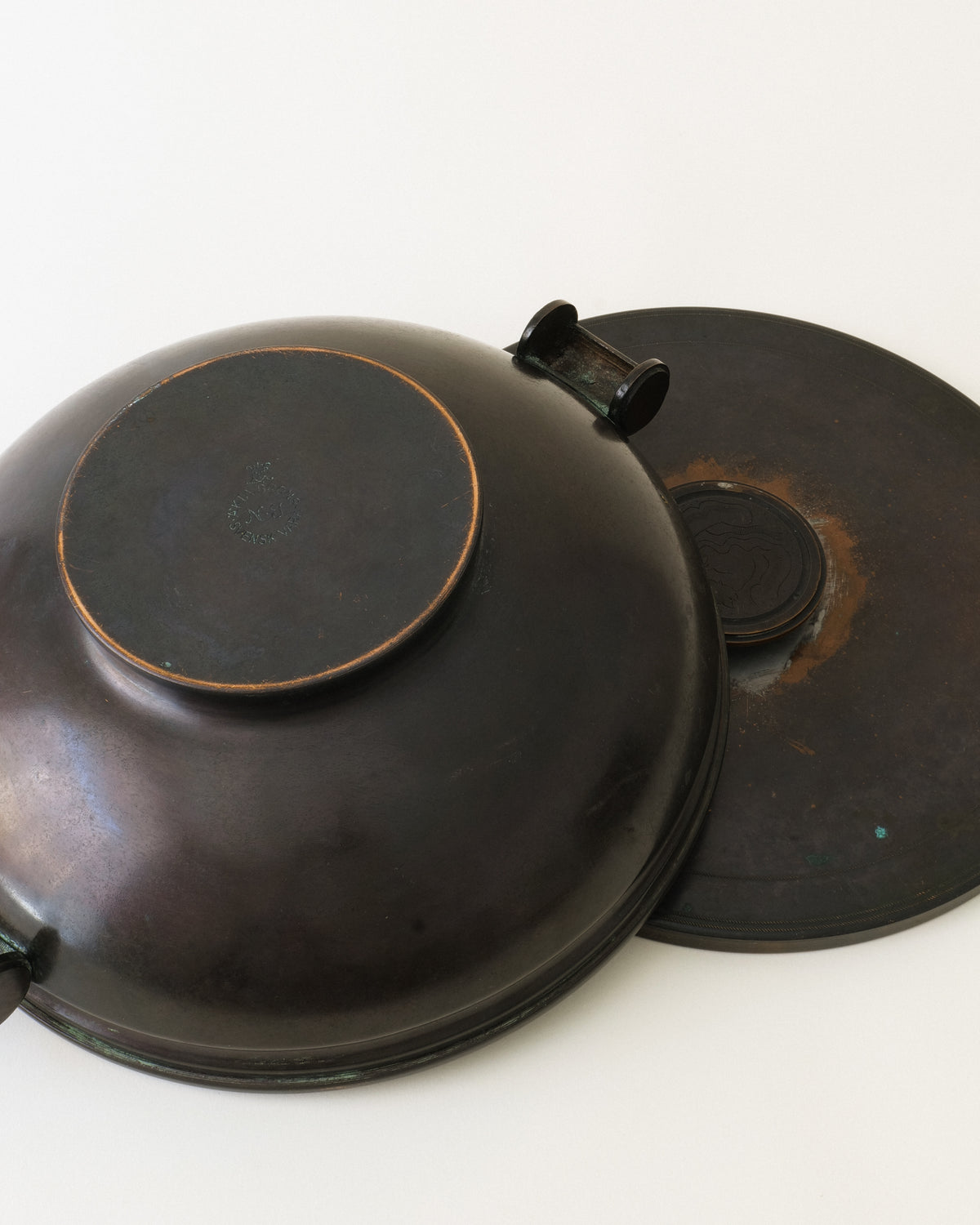 Underside of the Swedish bronze dish shown beside its fitted lid
