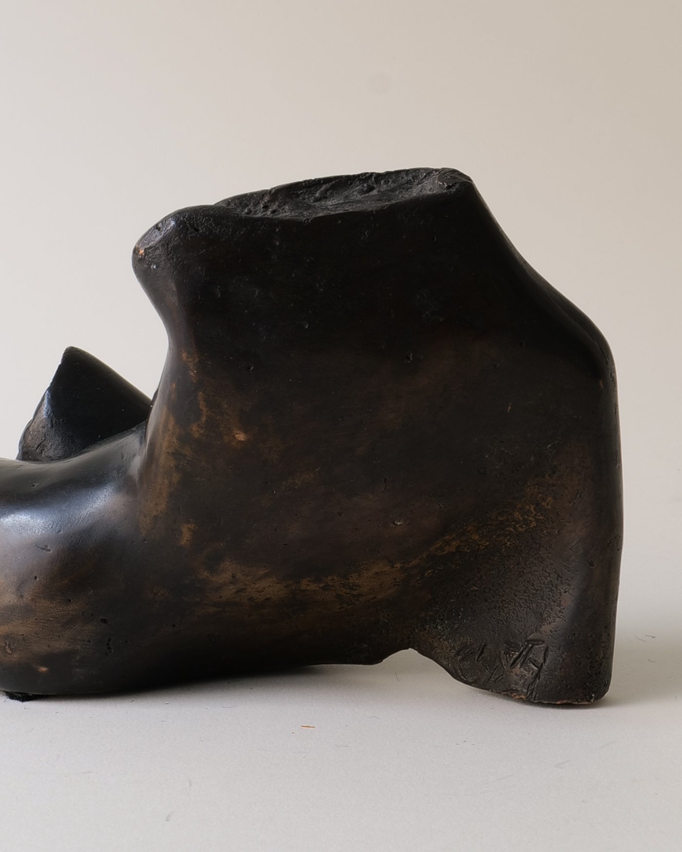 Black bronze sculpture of reclining figure on beige background