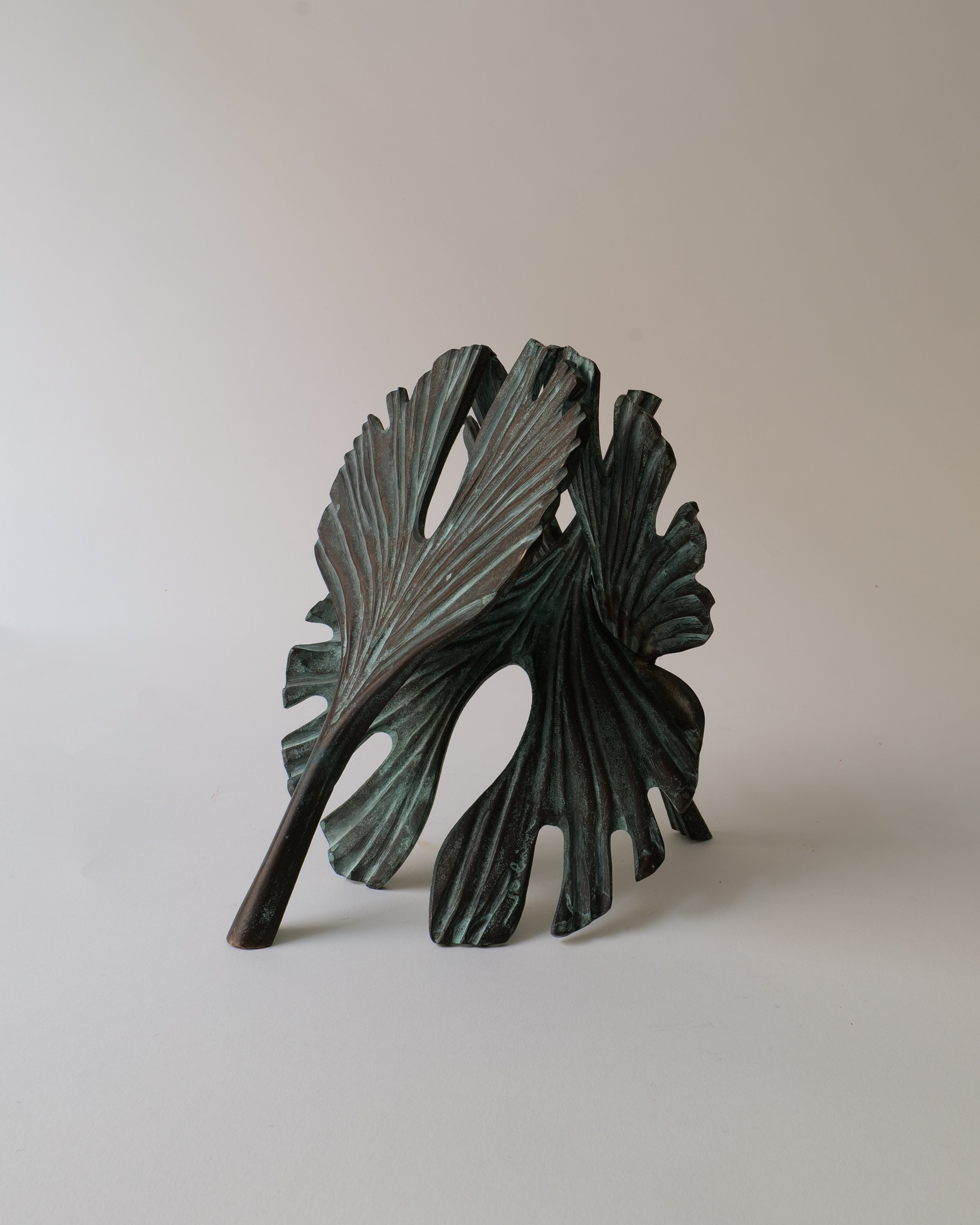 Bronze leaf-shaped sculpture on a beige background