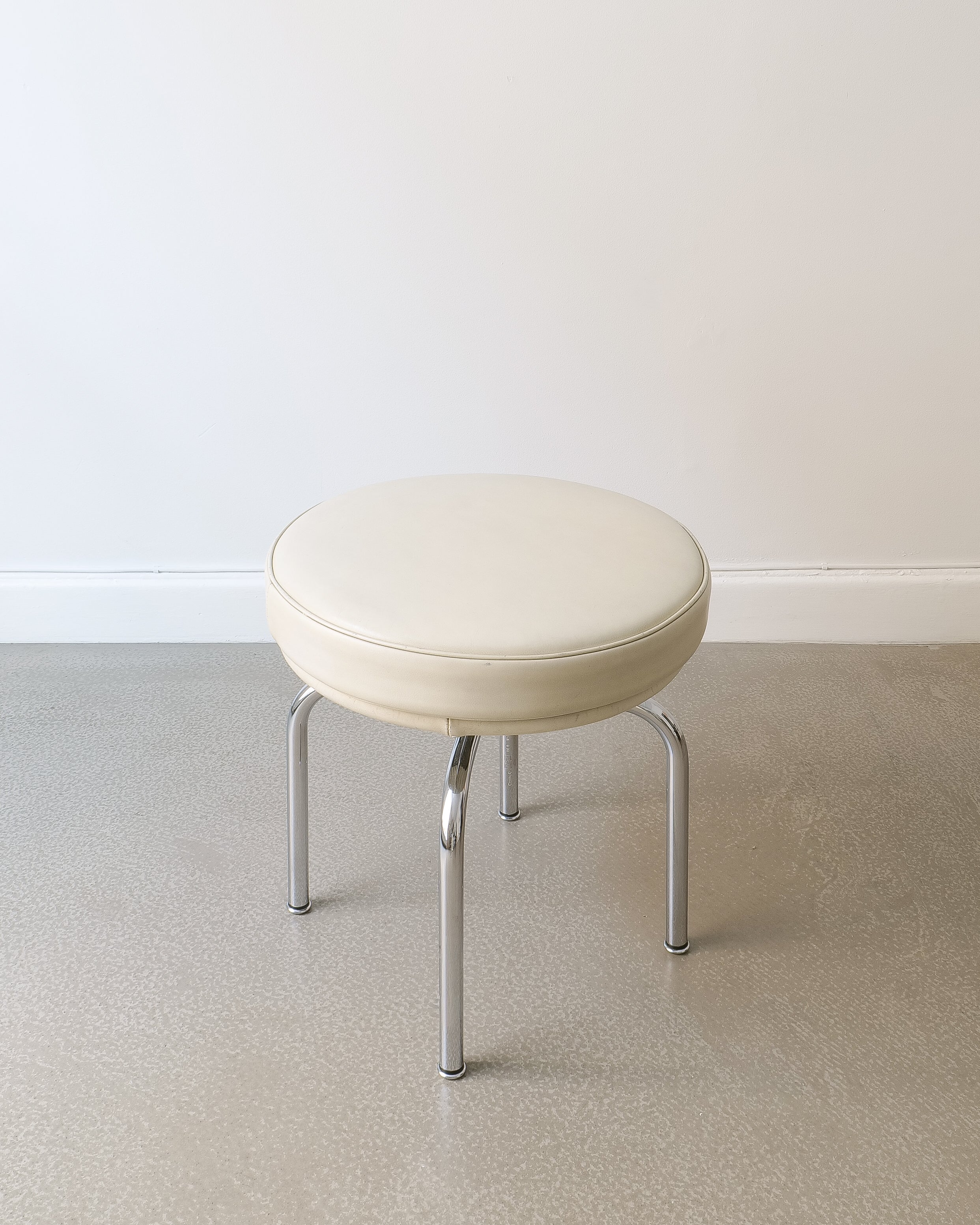 Charlotte Perriand LC8 stool, three-quarter view showing chrome legs and leather cushion