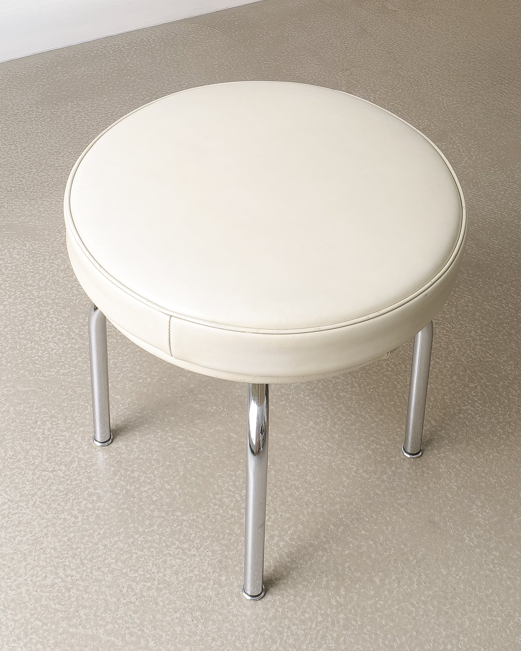 Charlotte Perriand LC8 stool, top-down view of circular beige leather cushion