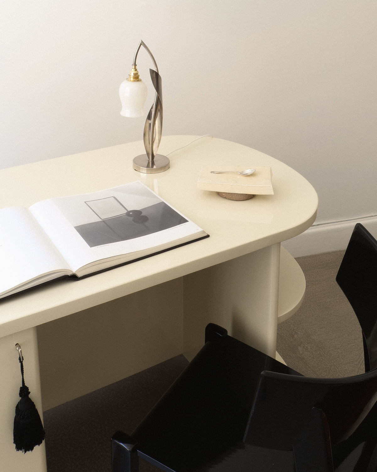 Chrome 1950s table lamp displayed on a curved white desk in a modern interior

