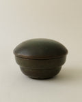 A patinated bronze lidded jar with an Art Deco design, stamped 'Gekko Brons', against a neutral background.