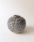 A gray and white stoneware ceramic vase with a textured surface and a narrow opening at the top.