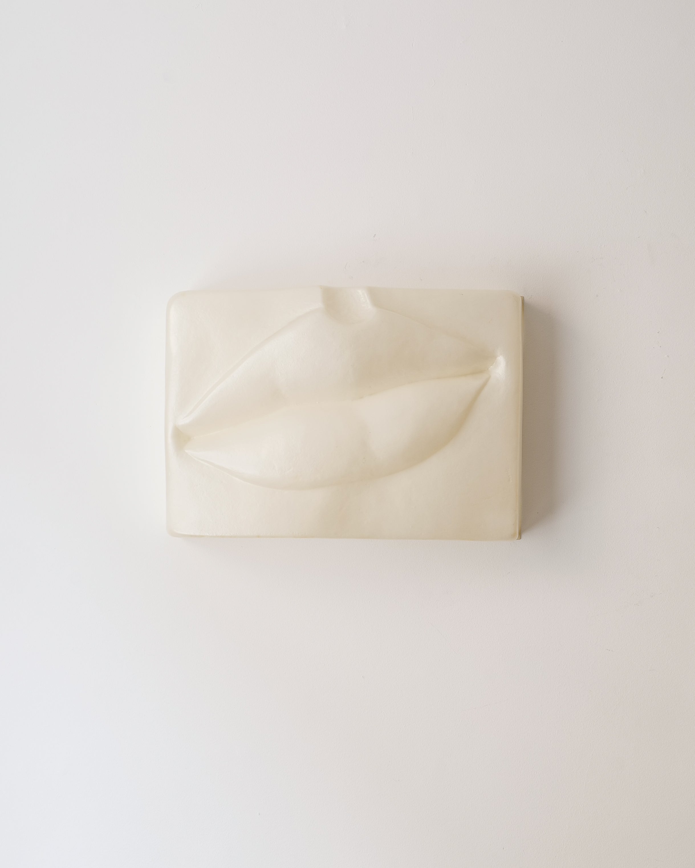 Beige wall sculpture of a mouth form on beige background by Swedish artist Hertha Hillfon.