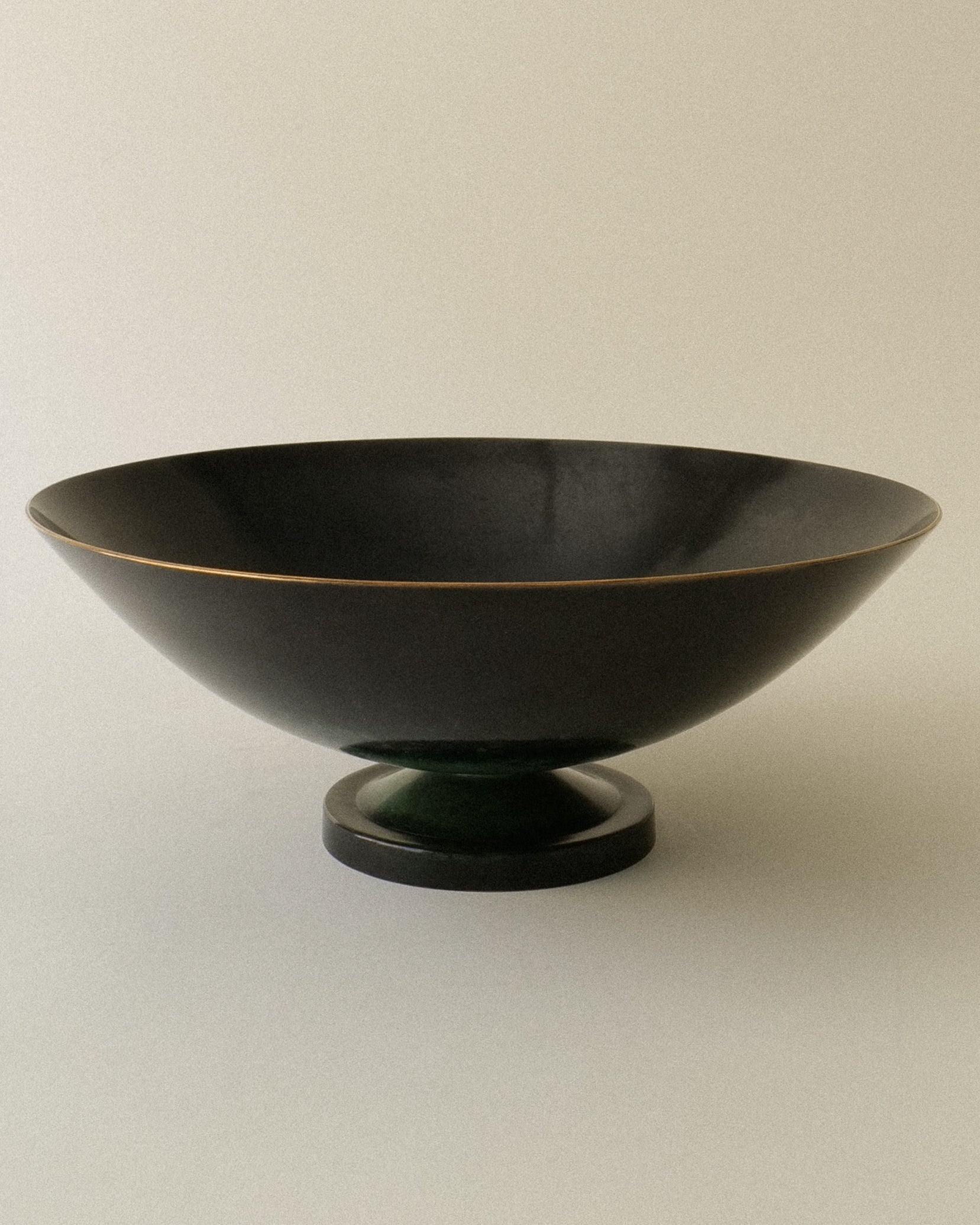 A patinated bronze raised bowl with a gold rim, displaying good wear consistent with its age and style.