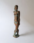 A bronze patinated plaster sculpture of a standing nude figure with a contemplative stance.