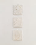 Three antique Tekniska Skolan plaster relief plaques with ornamental leaf motifs, hung vertically on a white wall.
