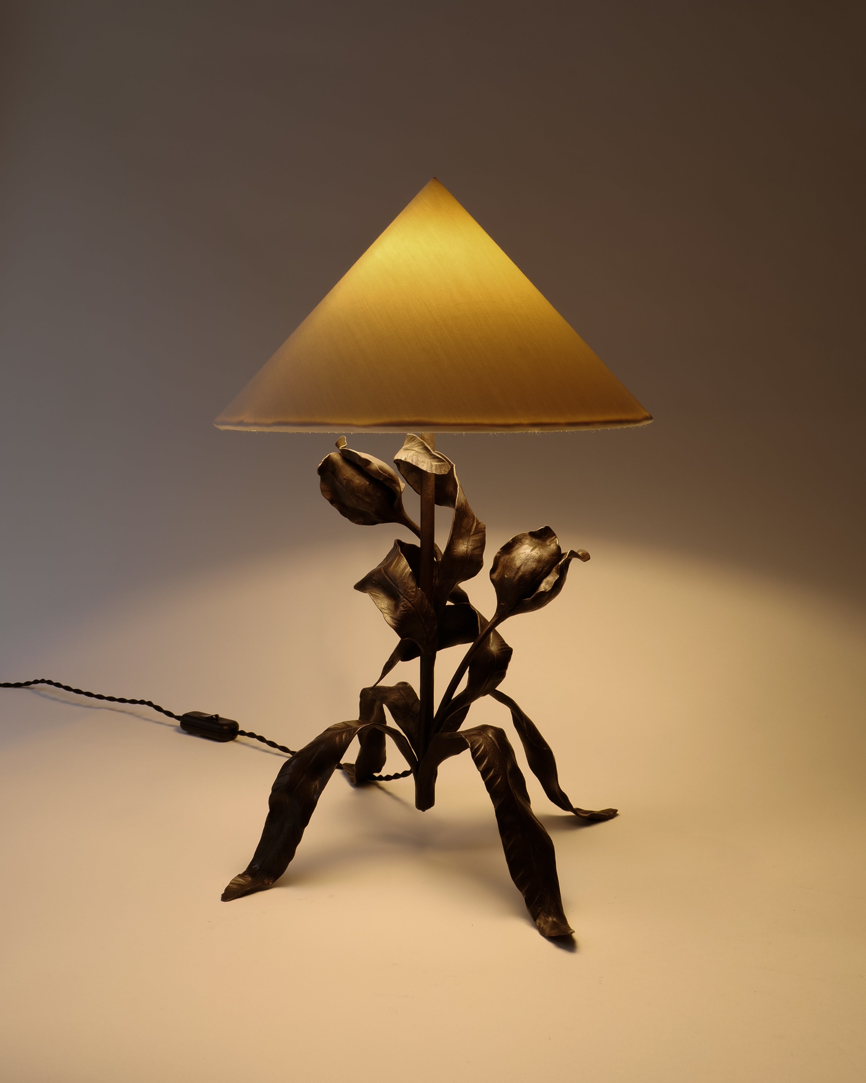 Art Nouveau table lamp with black metal base shaped like leaves on a white background