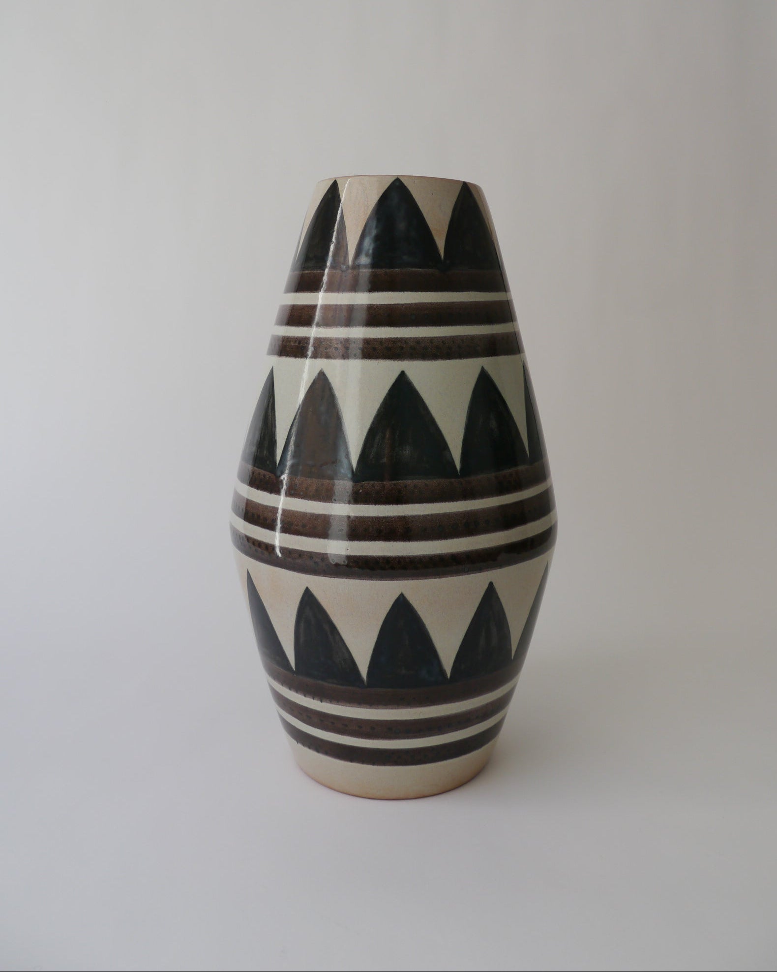 Painted zig-zag and stripe floor ceramic vase on white background.